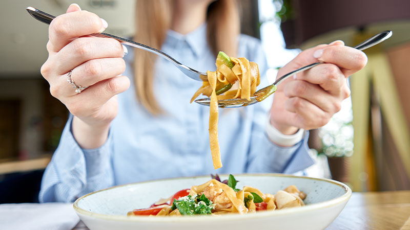 primo piano forchette che raccolgono le tagliatelle dal piatto